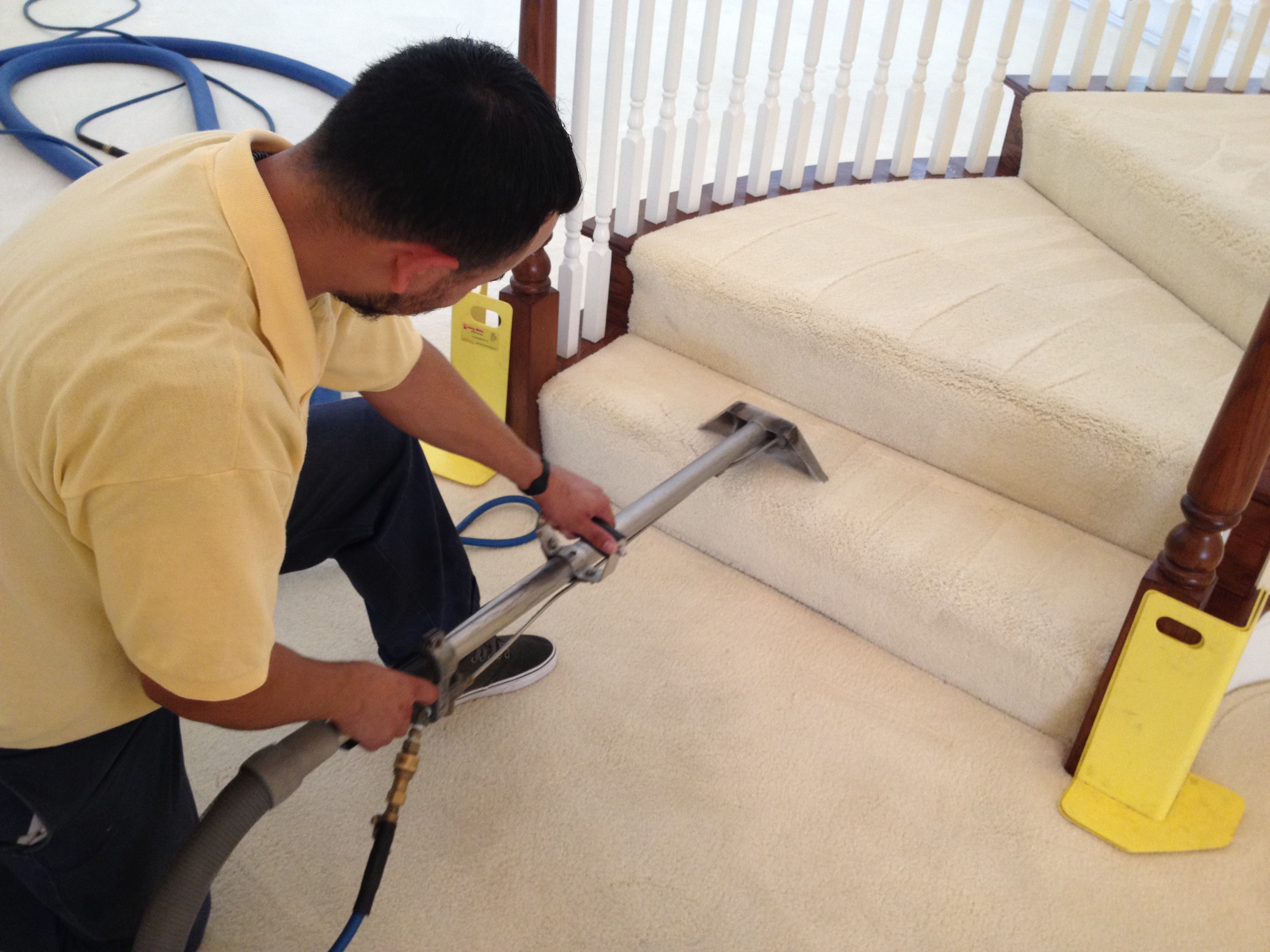 Technician cleaning carpeted stairs with a wand attachment